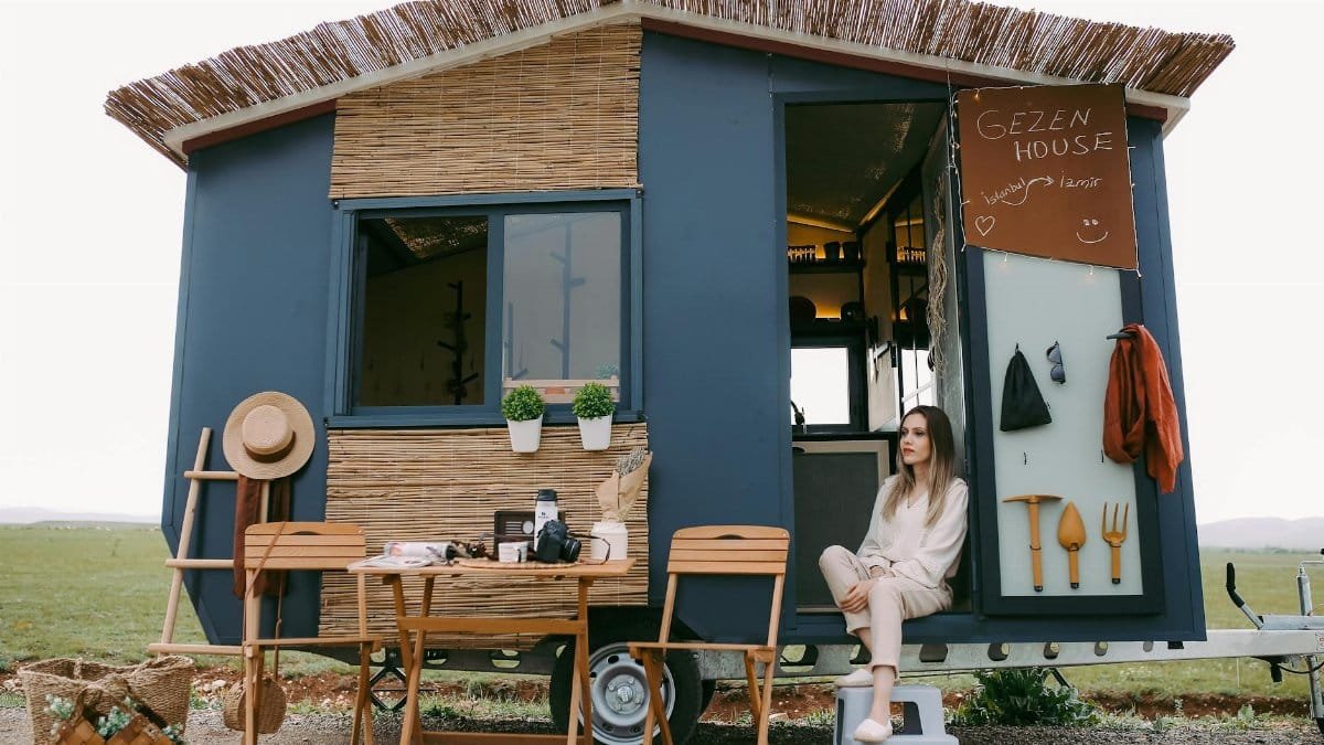 A woman enjoys a peaceful moment in a stylish mobile home, showcasing boho design.