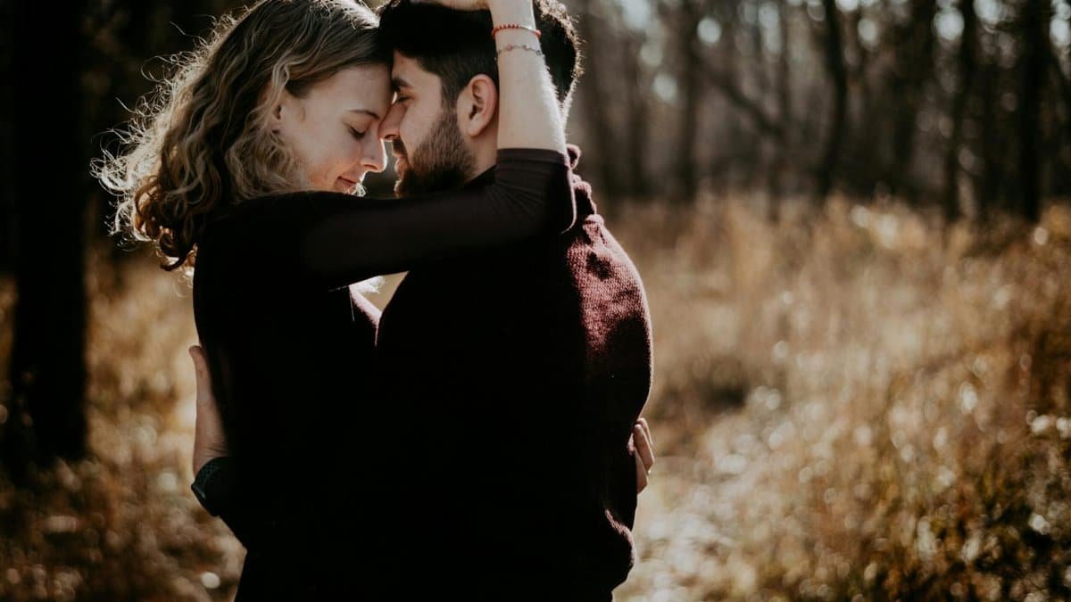 A loving couple embraces in a warm, romantic setting in Seattle's woodland.
