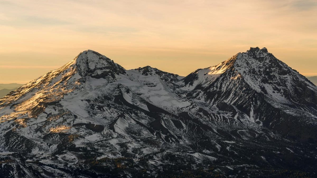 A breathtaking view of snowcapped mountains during sunset near Bend, Oregon, capturing the serene natural beauty.