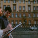 Two men engaging in conversation outdoors during dusk in an urban city setting, depicting everyday life.