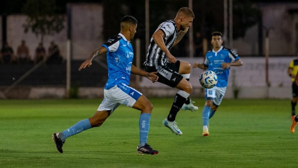 Two soccer players in mid-action during a competitive night match on the field.