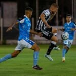 Two soccer players in mid-action during a competitive night match on the field.