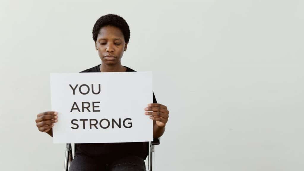 Woman holding 'You Are Strong' sign, promoting empowerment and motivation.