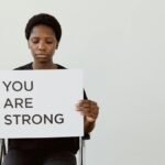 Woman holding 'You Are Strong' sign, promoting empowerment and motivation.