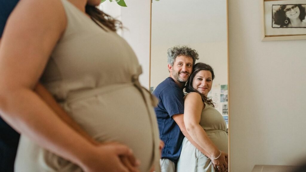 Joyful couple expecting a baby, embracing in front of a mirror indoors.