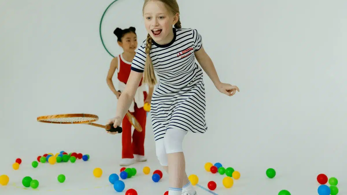 Two girls having fun playing indoors with rackets and colorful balls, full of joy.