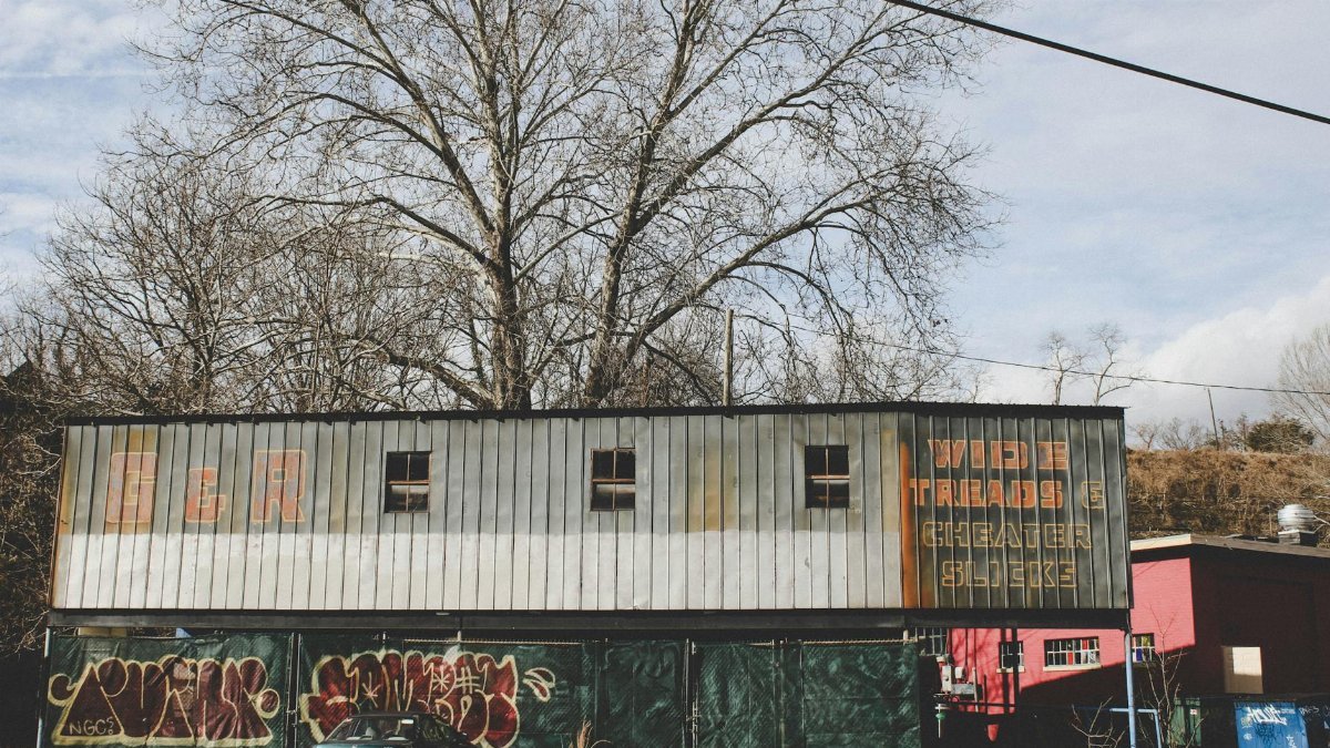 An old building with graffiti and abandoned car in Asheville, NC. Captures urban decay and street art.