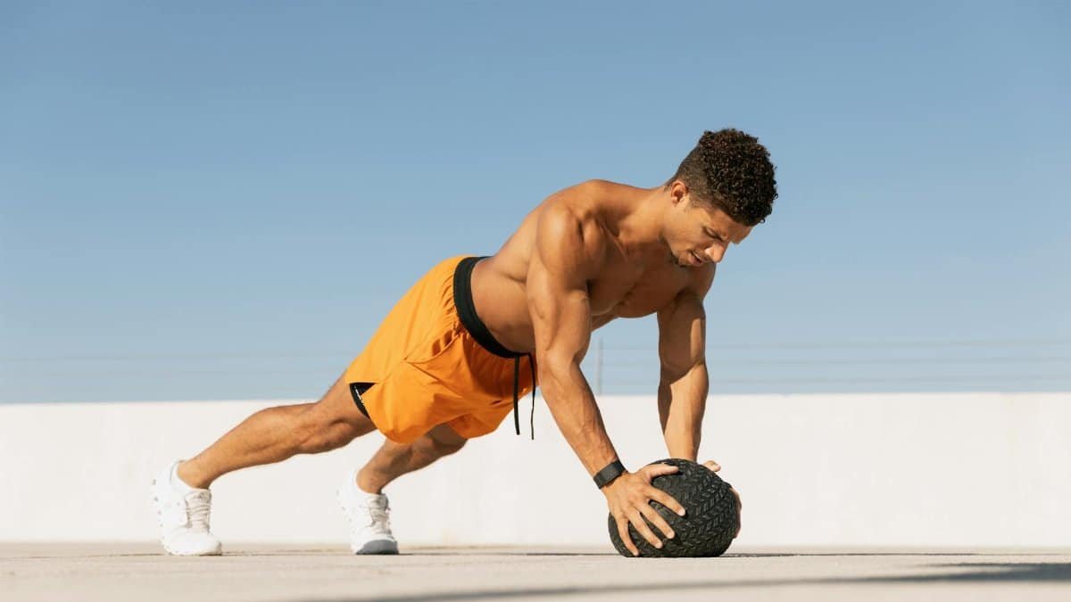 Athletic man performing a workout with a medicine ball on a sunny rooftop in Austin, Texas.