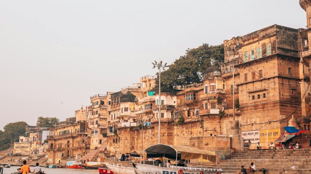 Picturesque view of Varanasi ghats along the Ganges River with bustling boats and ancient architecture.
