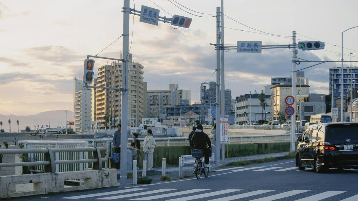 A serene evening at a coastal urban area with traffic lights, buildings, and a cyclist in Japan.