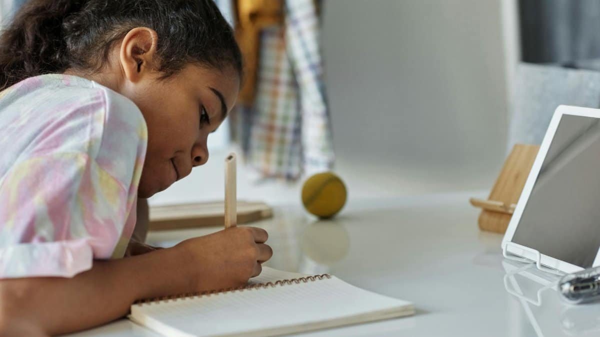 A young girl concentrating on homework at home using a tablet.