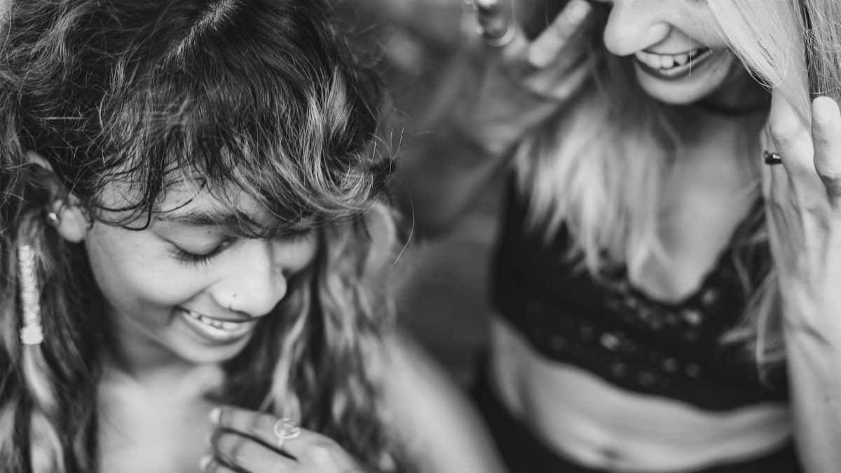Two women laughing and enjoying a moment of friendship in black and white photography.
