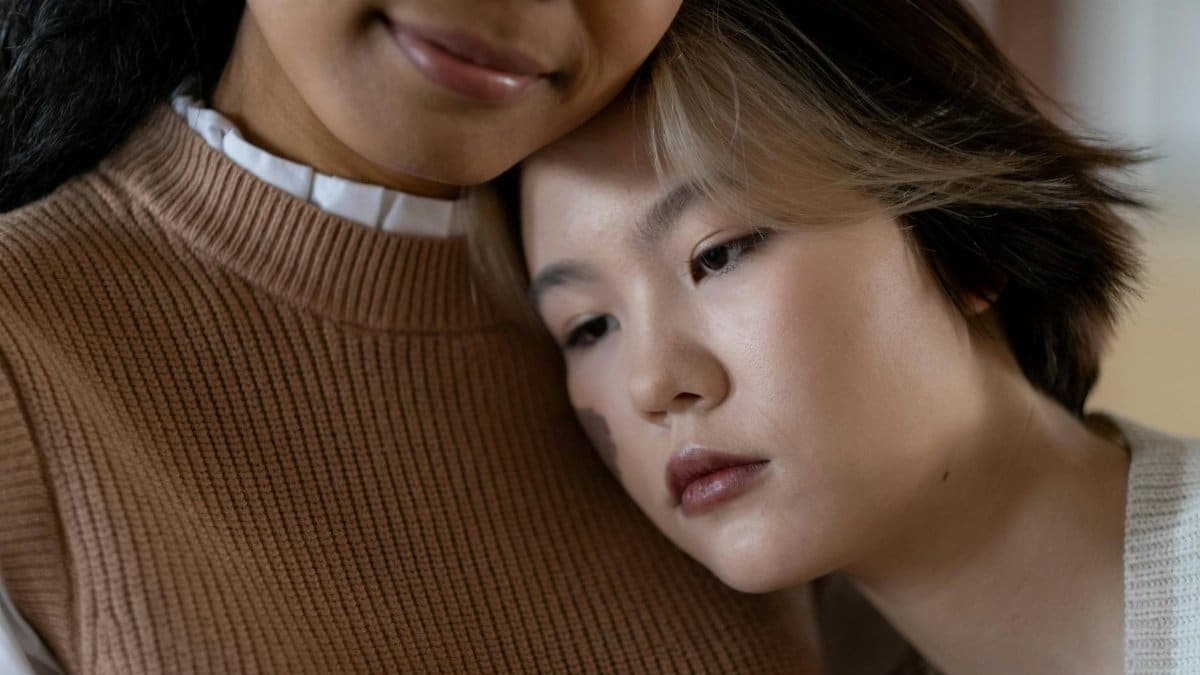 Close-up of two women, one leaning on the other's shoulder, expressing care and togetherness.