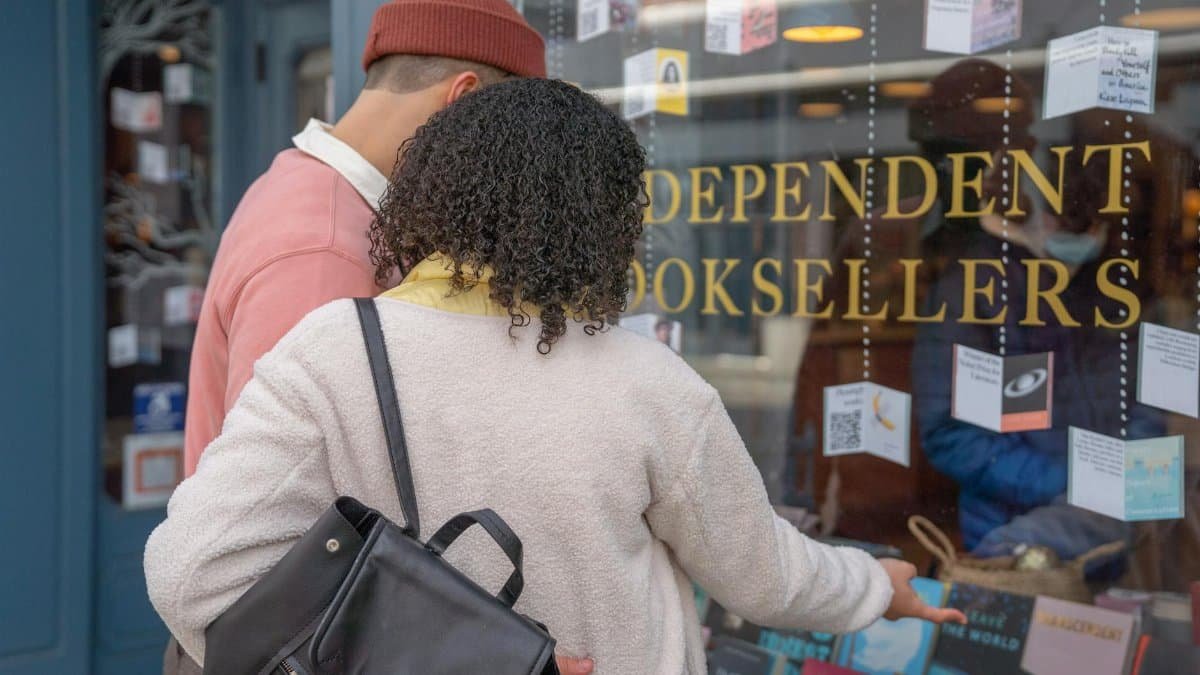 A young couple explores book selections at an independent bookstore window display.