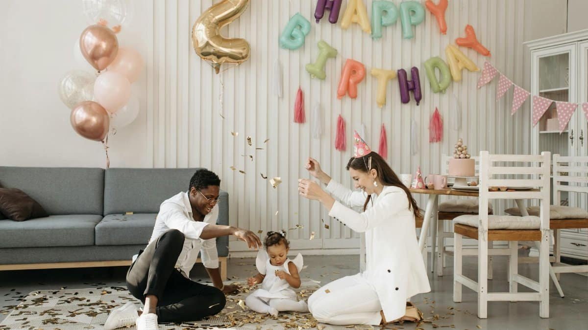 A joyful indoor birthday celebration for a two-year-old with balloons and confetti.