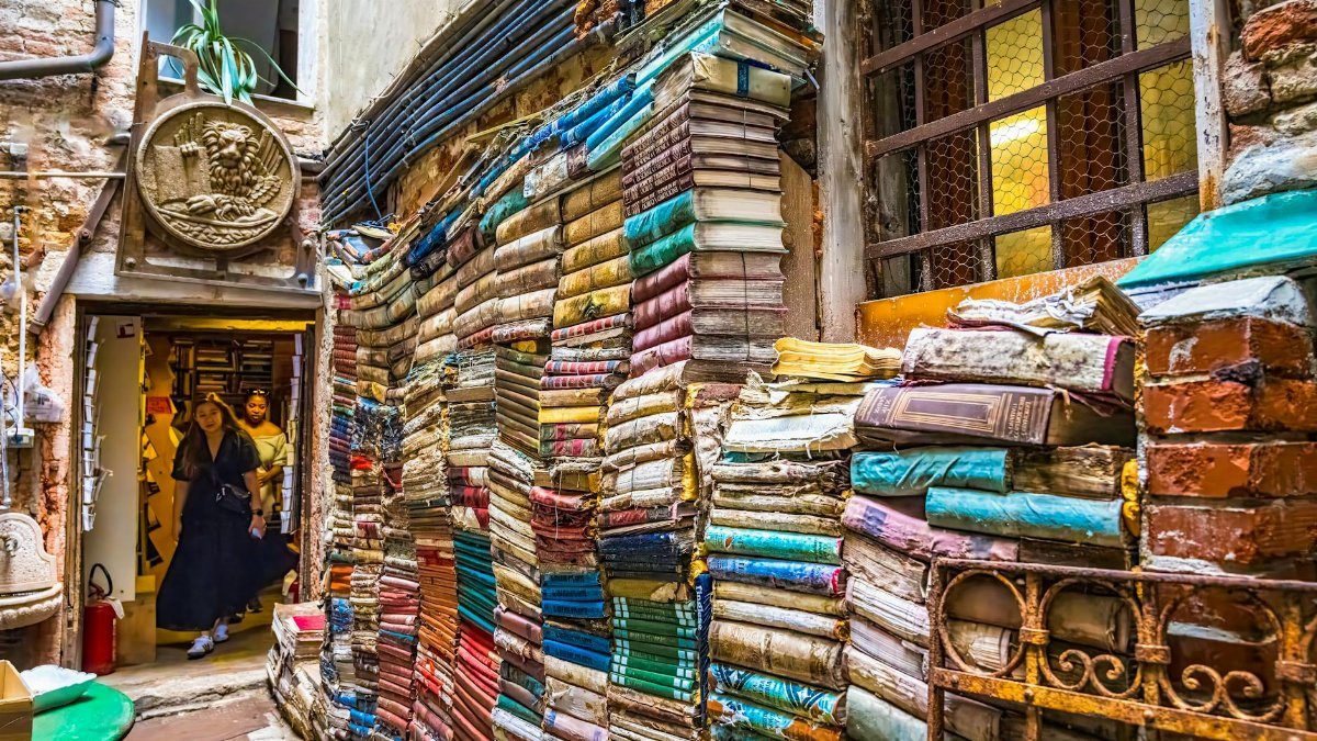 Vibrant stacks of books lining a charming alley in Venice, Italy, evoking a whimsical literary escape.