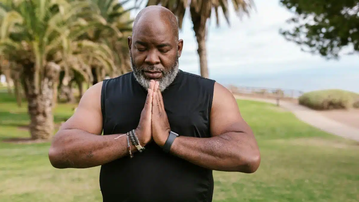 Man practicing yoga outdoors, promoting relaxation and mindfulness in a serene park environment.