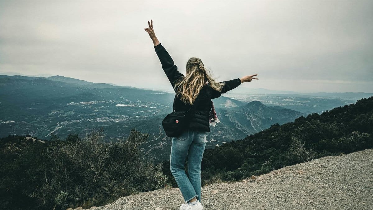 Carefree woman stands on a mountain in Sintra, Portugal, embracing nature's beauty.