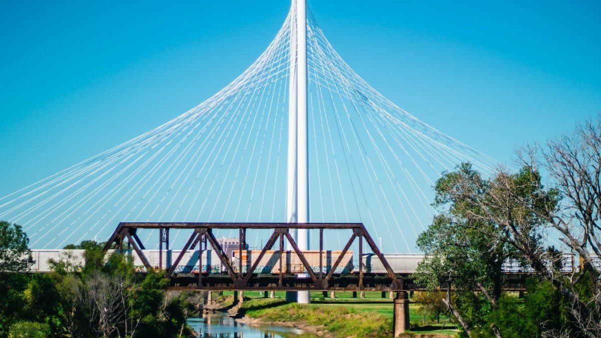 View of the Margaret Hunt Hill Bridge with a train passing underneath in Dallas, Texas.