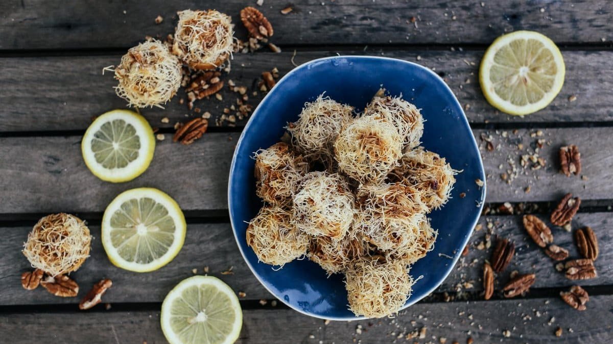 A rustic presentation of sweet dessert balls with lemon slices and pecans on a wooden background.