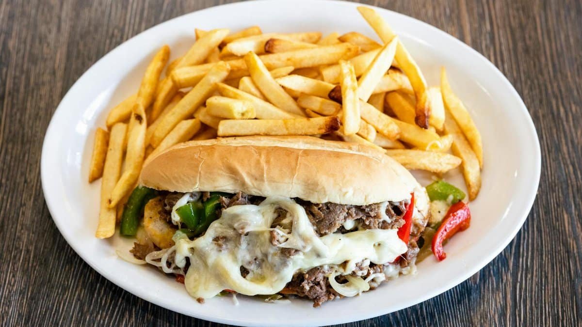 Mouth-watering Philly cheesesteak with melted cheese and french fries.