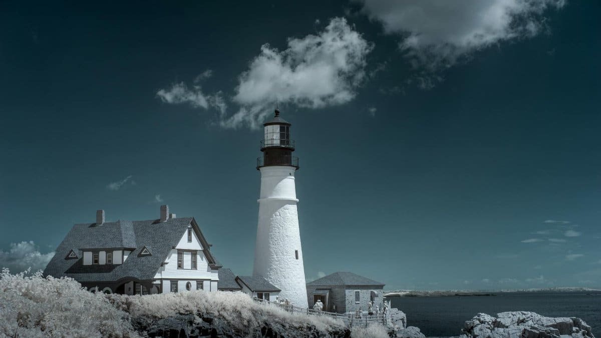A picturesque view of the iconic Portland Head Light under a cloudy sky in Cape Elizabeth, Maine.