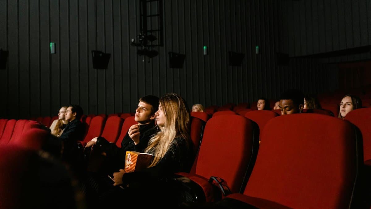 Audience enjoying a movie with popcorn in a dimly lit theater, capturing the cinematic experience.