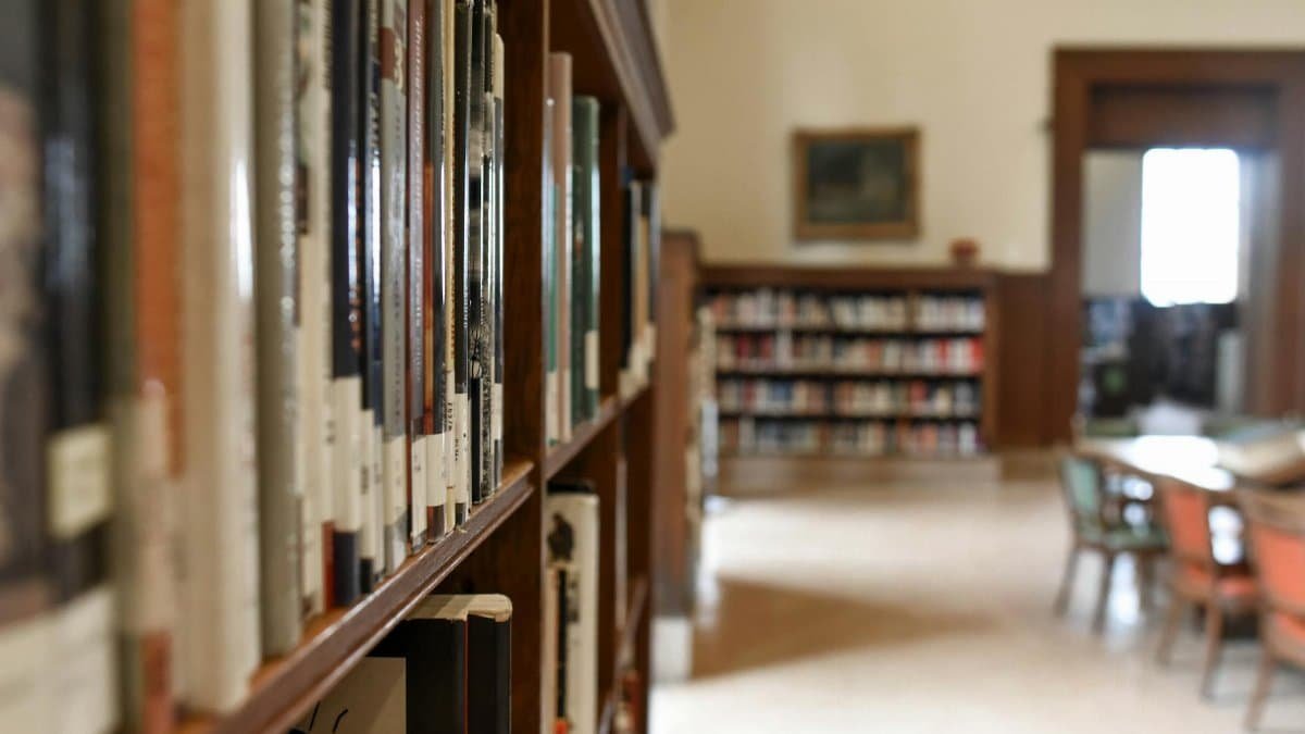 A quiet library interior featuring bookshelves, seating, and a study area for learning and reading.