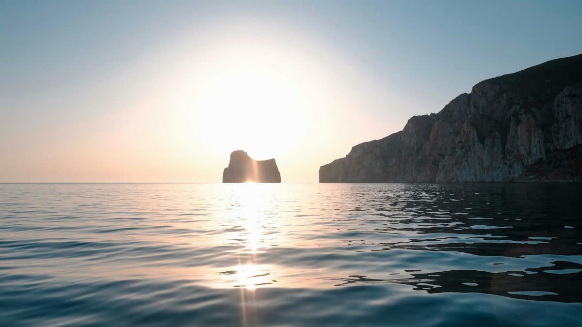 Peaceful sunrise over calm sea with rock formations and cliffs. Perfect for nature enthusiasts.