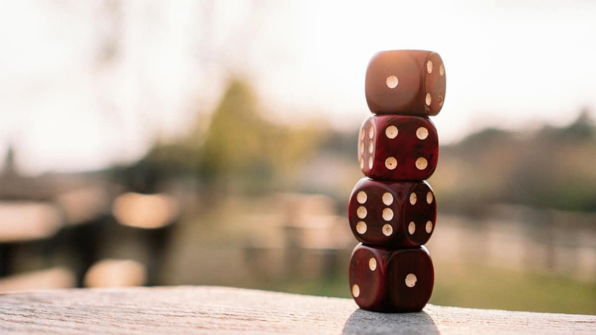 Set of red dice stacked together on wooden table placed on sunny terrace in daylight