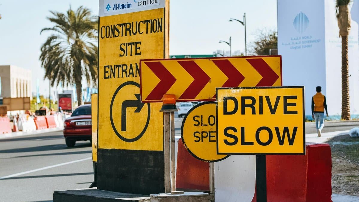 Contemporary city road on sunny day with various traffic signs warning about driving slow because of construction site entrance