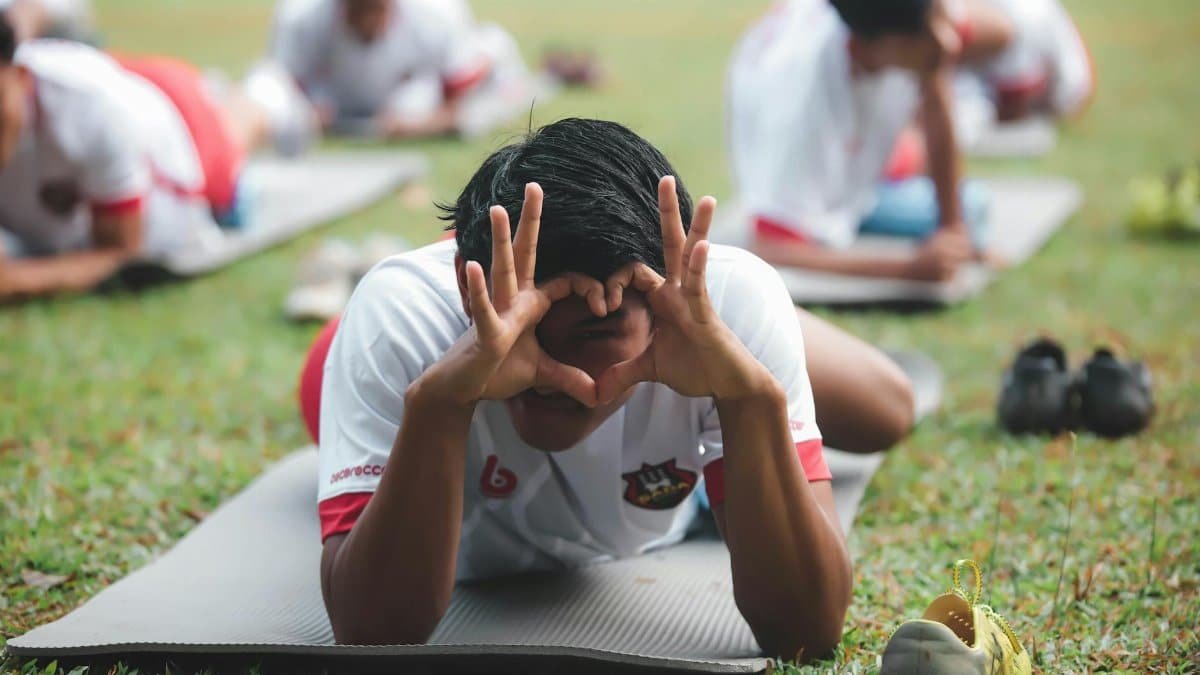 Young athletes stretching on mats in a Jakarta park during a team practice.
