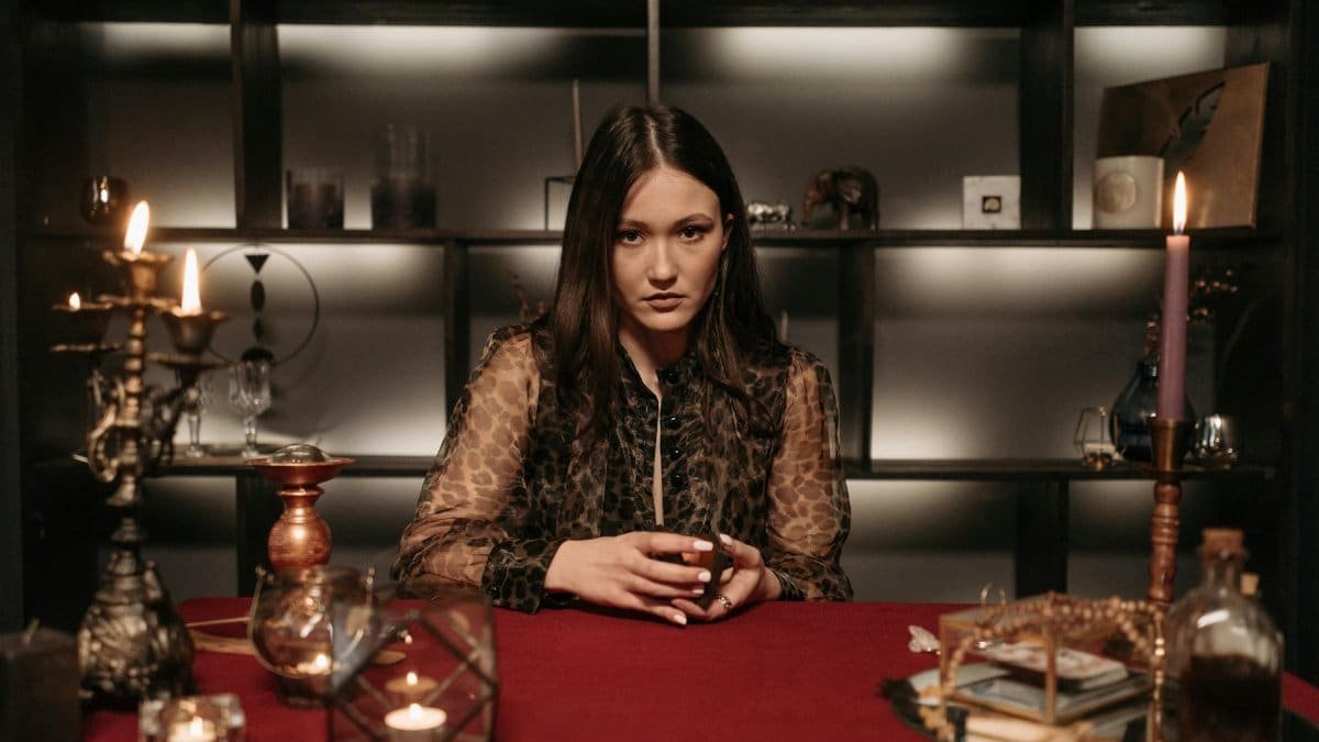 A mysterious woman in a dimly lit room, engaged in fortune telling with candles and tarot.