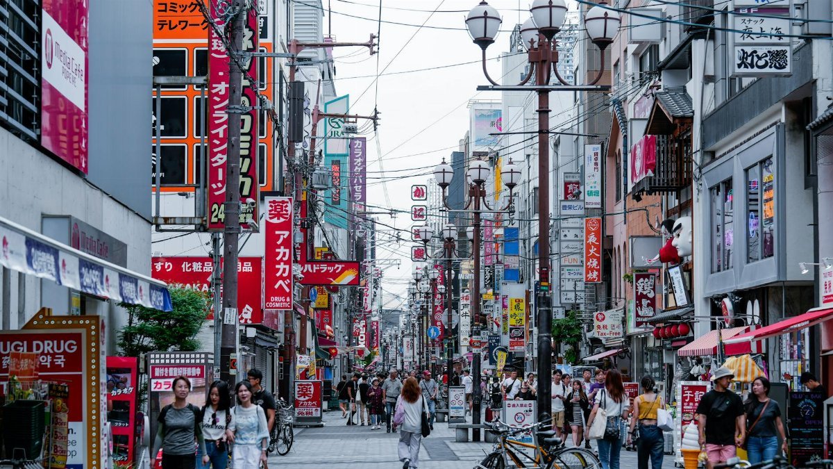 Busy pedestrian street in Osaka with vibrant signs and bustling activity.