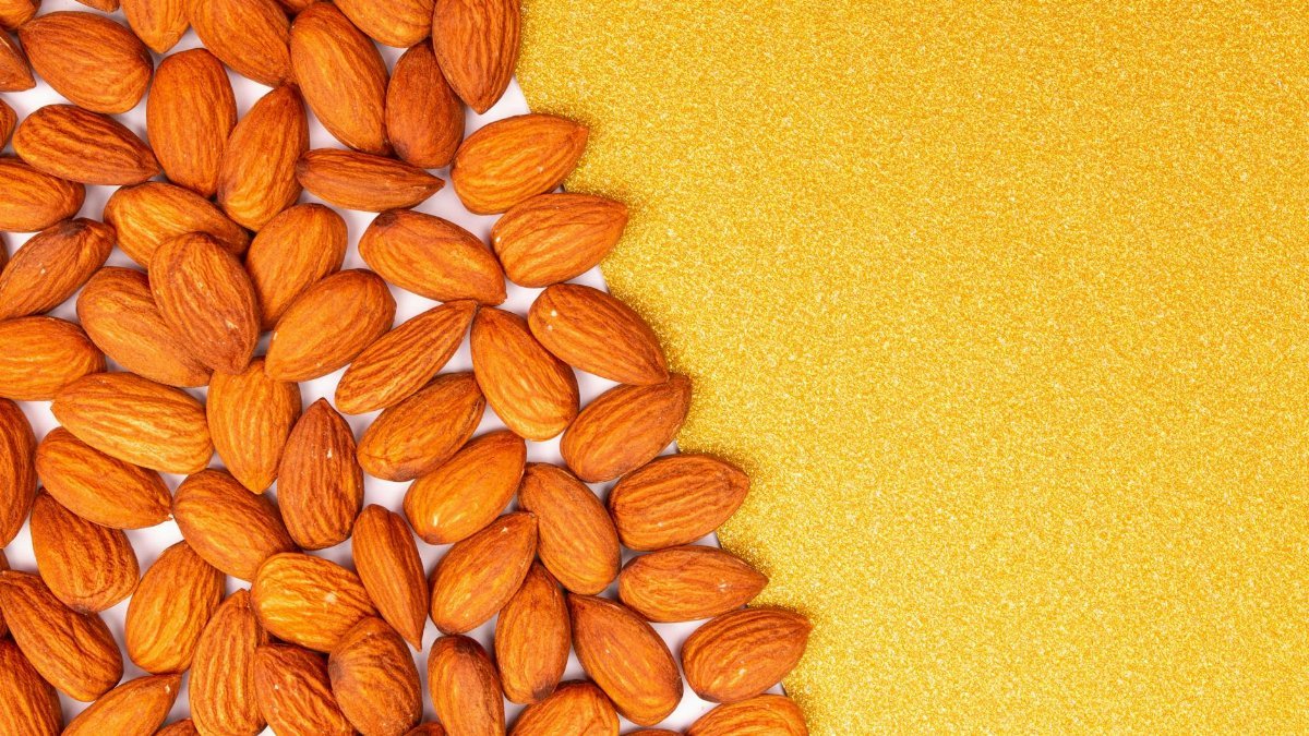 Flat lay of organic almonds on a bright orange background with space for text.