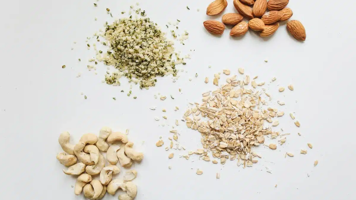 Top view of almonds, cashews, oats, and hemp seeds on white background.