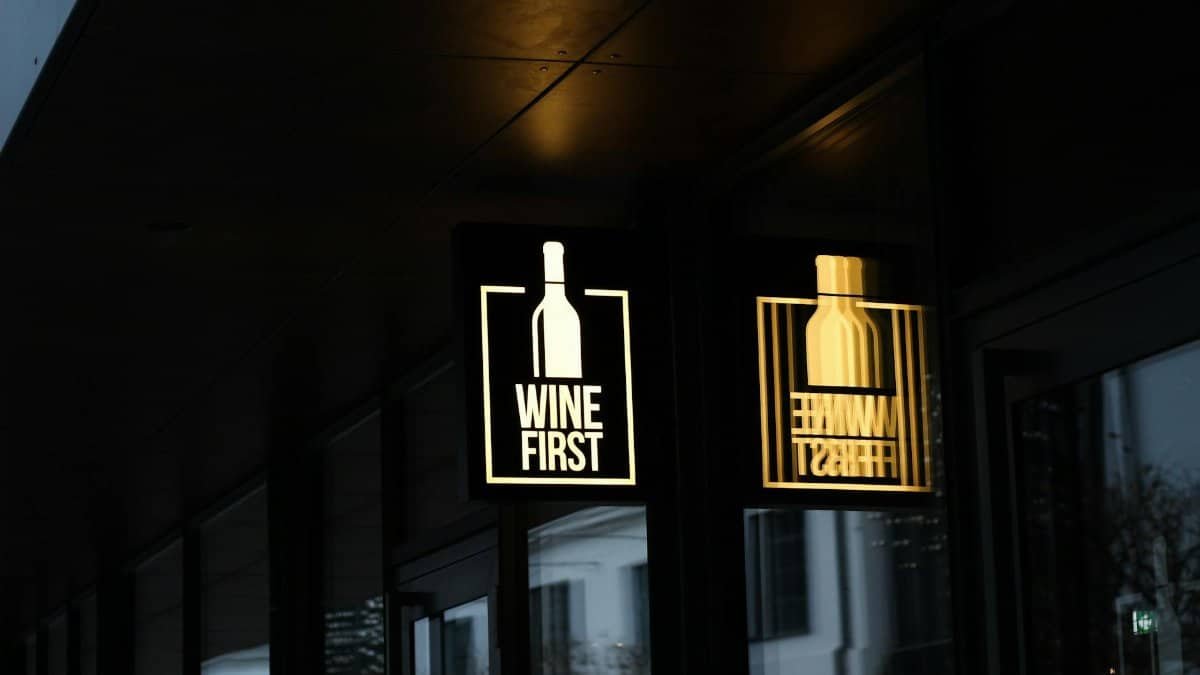 Illuminated 'Wine First' sign in Warsaw, reflecting a cozy nightlife scene.