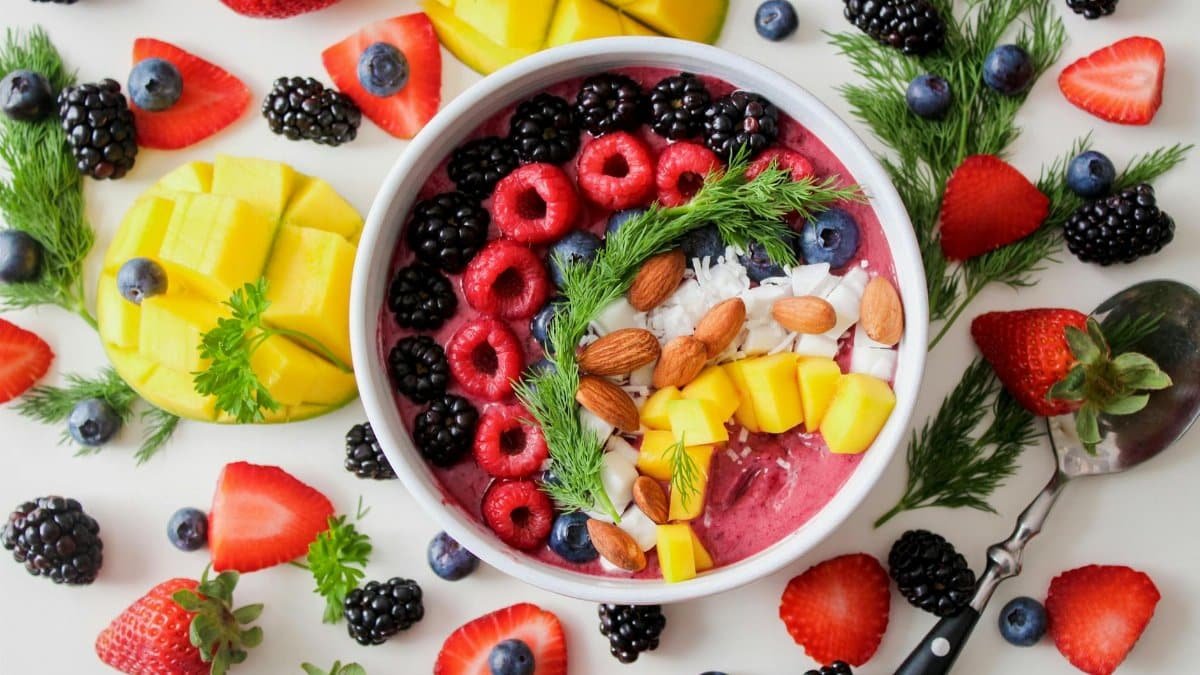 A vibrant, healthy fruit smoothie bowl topped with fresh berries, mango, and almonds.
