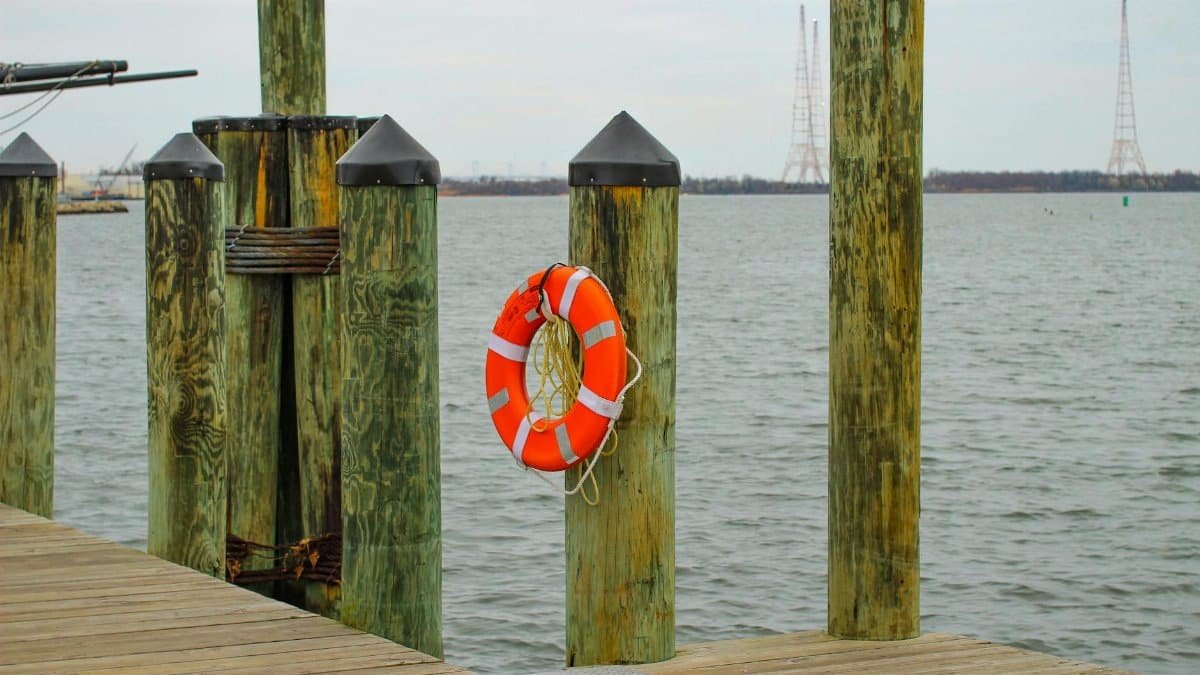 Wooden dock in Annapolis, Maryland with a bright orange life buoy overlooking the calm Chesapeake Bay.