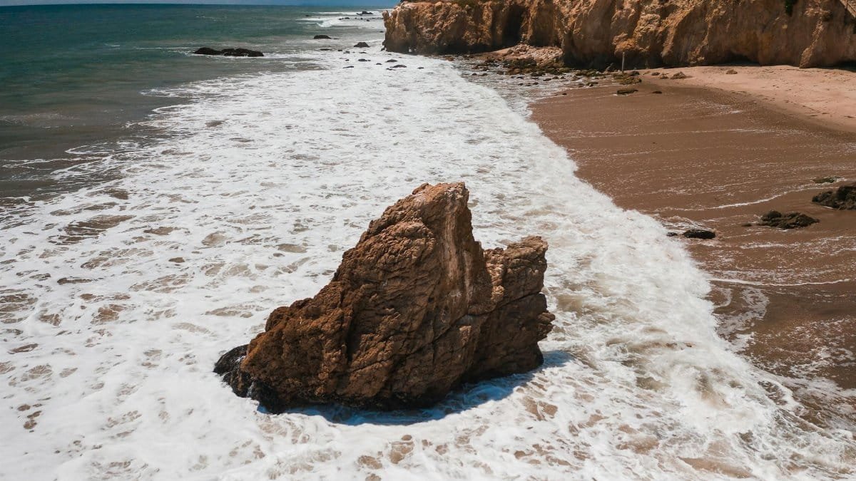 Captivating seascape featuring ocean waves crashing against rugged coastal rock formations.