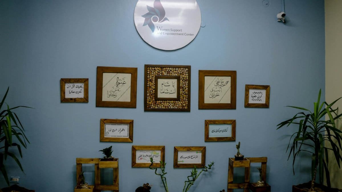 Wall decorations in a Women Support and Empowerment Center featuring framed calligraphy and plants.