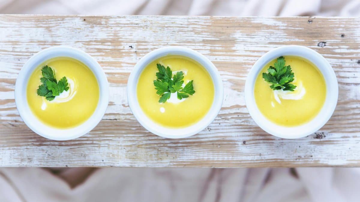 Top view of three bowls of vibrant leek and potato soup garnished with fresh parsley.