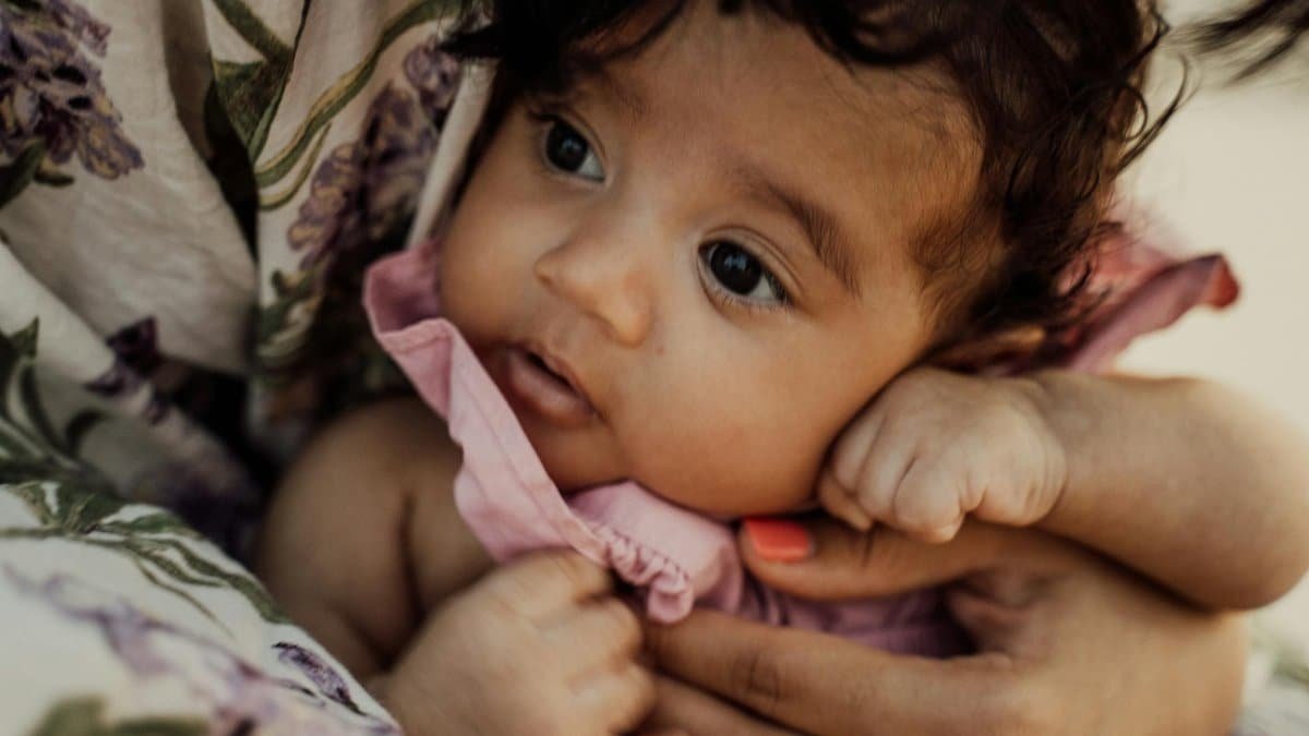 Close-up of a baby being gently held by a mother, showcasing love and warmth.