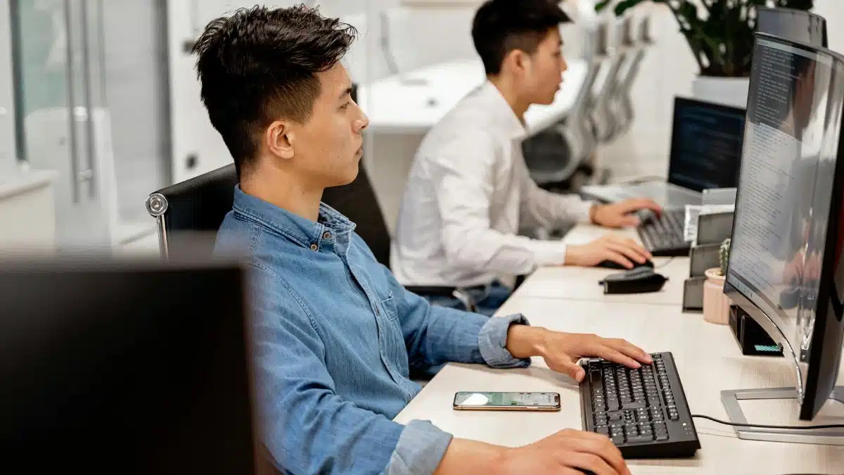 Young professionals working on computers in a modern office environment, focused on their tasks.