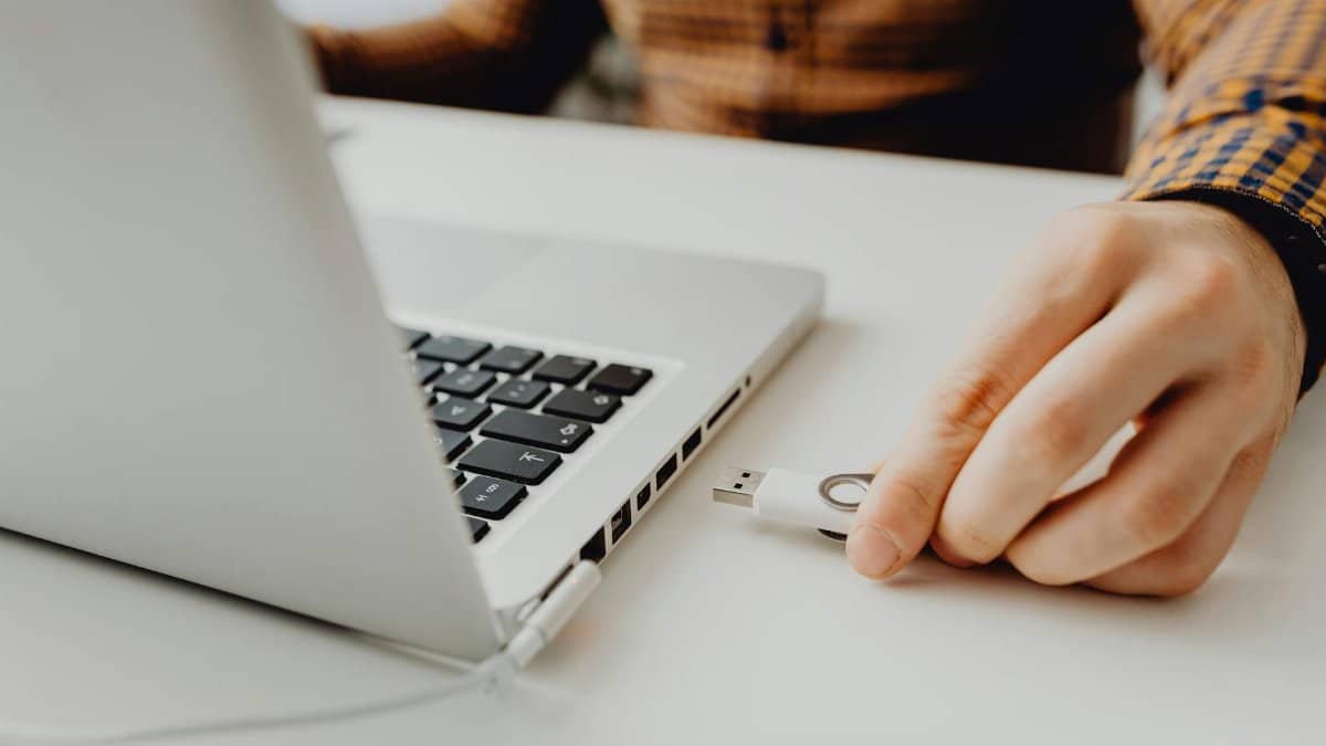 Close-up of a person inserting a USB drive into a laptop, symbolizing technology and data connection.
