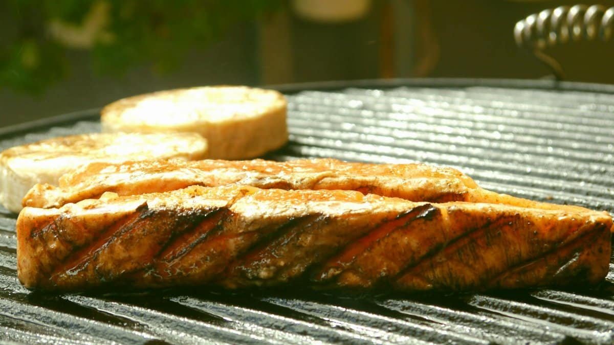 Close-up of grilled salmon steak on a barbecue grill outdoors.