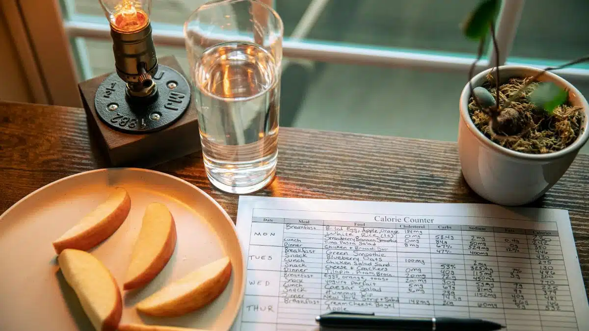 A cozy desk setup with apple slices, calorie counter, and water glass in warm lighting.