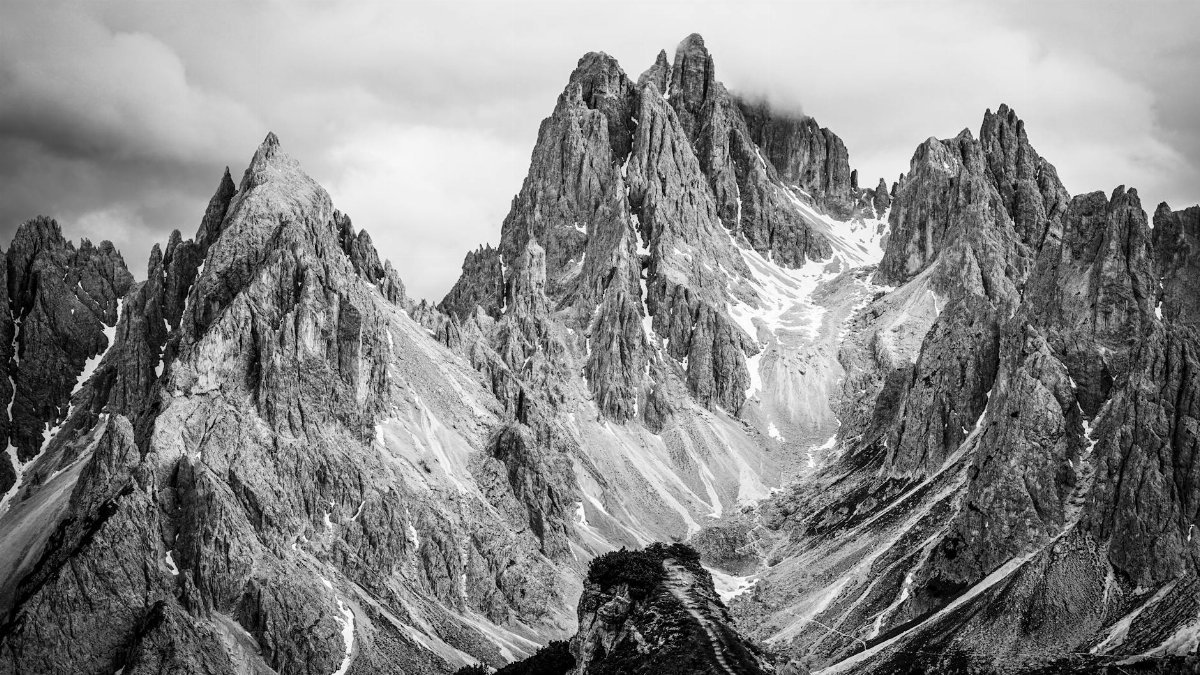 Striking black and white photograph of jagged mountain peaks under a cloudy sky.