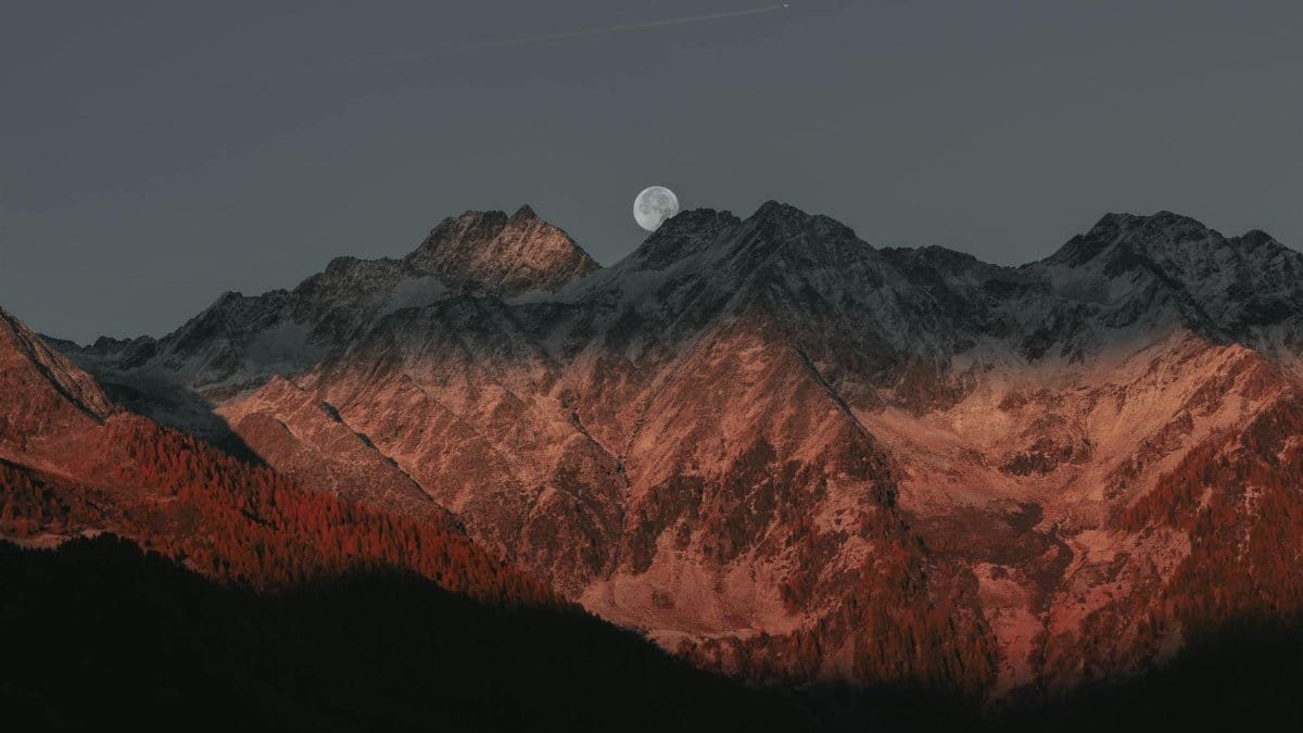 Stunning view of mountain peaks under moonlight with a twilight glow creating a dramatic landscape.
