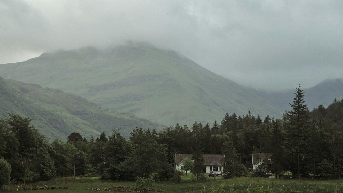 Peaceful scene of a misty mountain in the Scottish Highlands with a rural house.